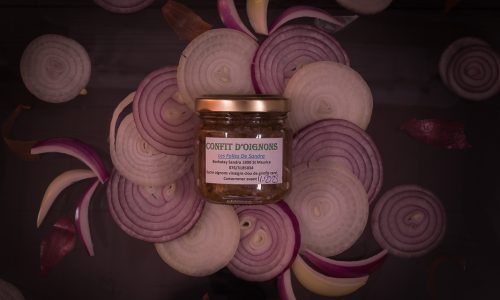 Photo artistique de compotée d'oignons agrémentée d'un arrangement de rondelles d'oignon en forme de fleur.