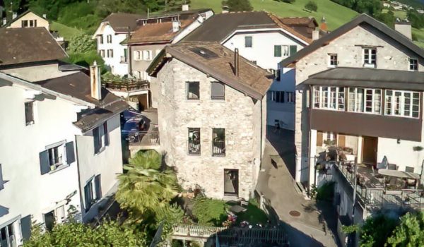 Vue aérienne d'une maison en pierre éclairée par le soleil.