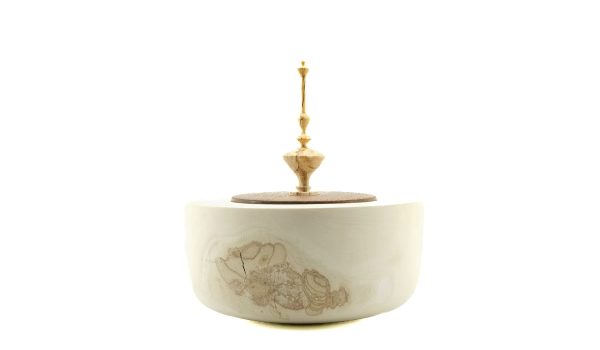 Photo sur fond blanc d'un bol en bois orné d'un fleuron, soulignant le savoir-faire artisanal et la beauté du travail manuel.
